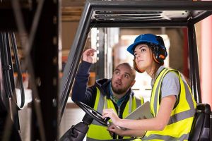 A young female forklift driver is being trained 