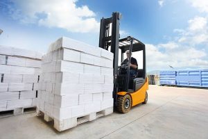Forklift loader making warehouse works outdoors by stacking boxes.